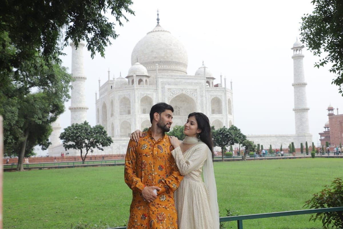 A couple photographed on the lawns with the Taj Mahal behind them