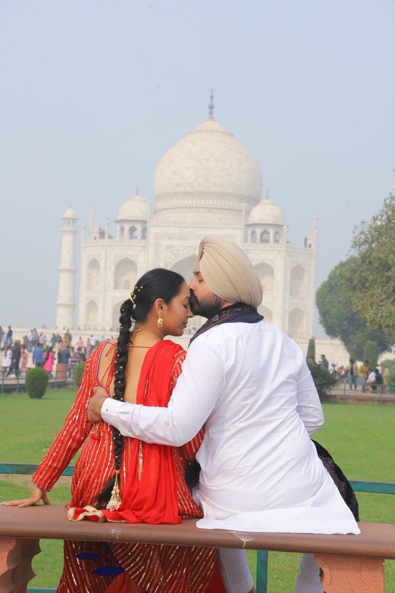 A couple sharing a moment on a bench with the Taj Mahal behind them
