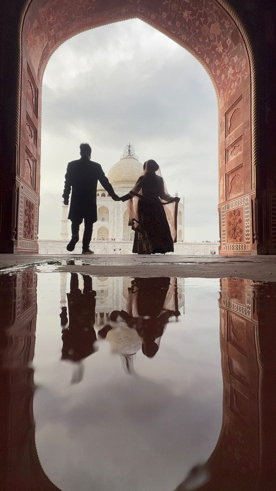 A couple silhouetted in the great gateway arch, reflected in the water below
